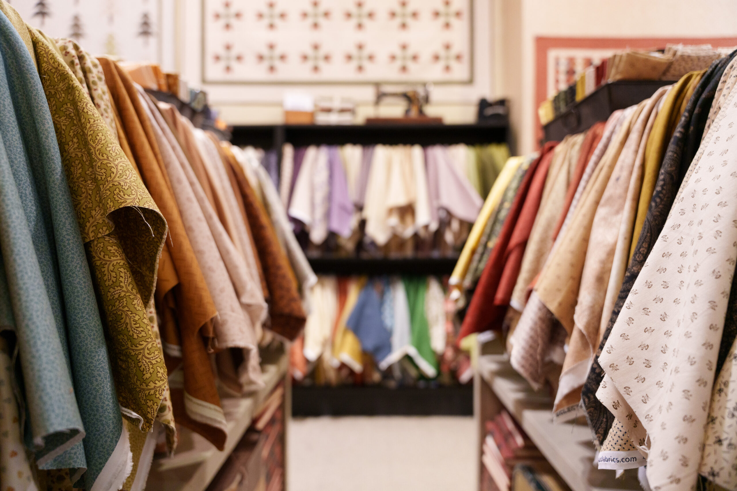 Shelves filled with neatly folded, variously colored and patterned fabric in a fabric store.