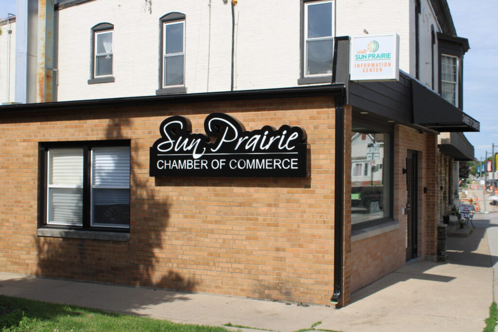 A brick building with a sign reading "Sun Prairie Chamber of Commerce" and a smaller sign above the door for the Sun Prairie Information Center.